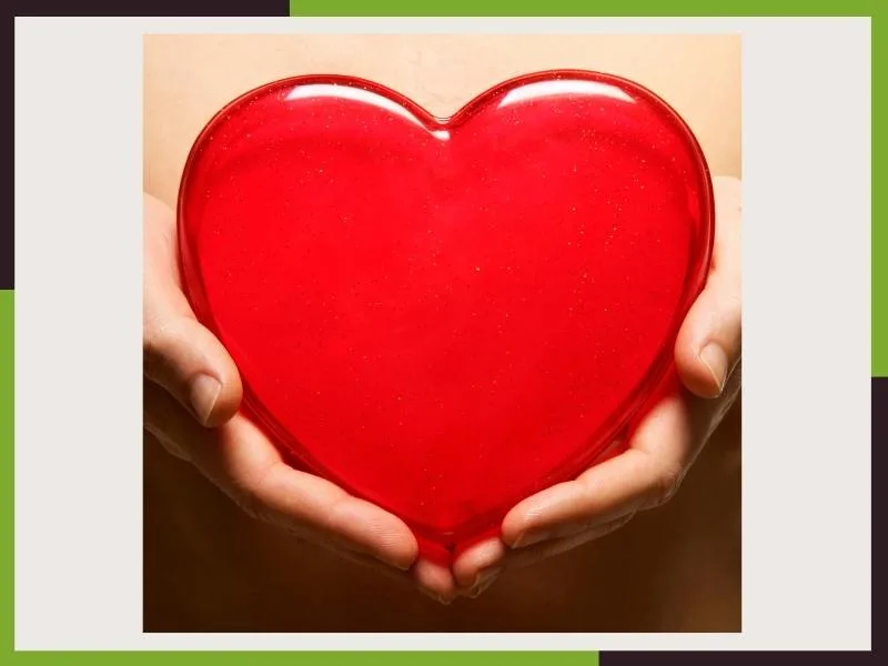 Corazón rojo sostenido entre las manos como símbolo del amor y la apertura del chakra Anahata