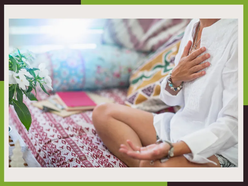 Persona meditando con una mano sobre el pecho, en la zona del chakra Anahata